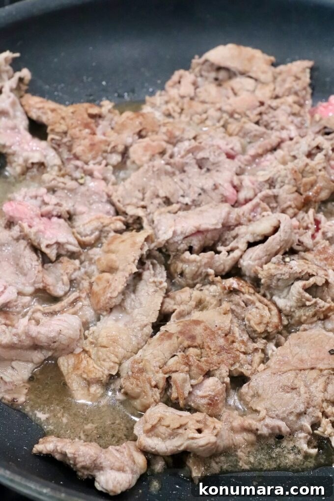 thinly sliced cooked steak in a skillet