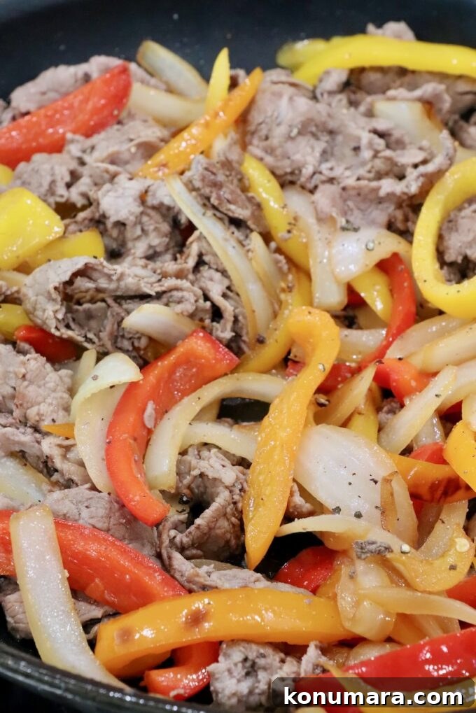 cooked steak, bell peppers, and onions in a skillet