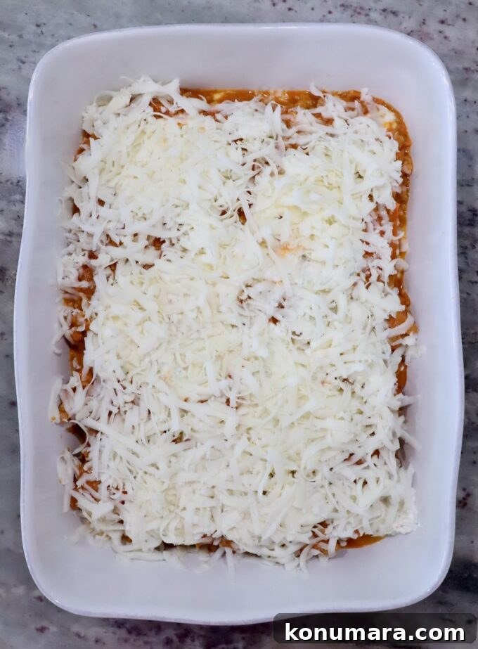 Baked Butternut Squash Ravioli with Brown Butter and Sage 9 White rectangular baking dish filled with layered pumpkin ravioli, topped with shredded mozzarella cheese.