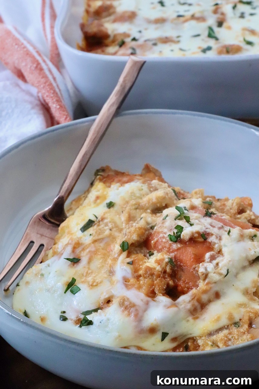 Baked Butternut Squash Ravioli with Brown Butter and Sage 10 A close-up of a creamy, cheesy pasta bake in a bowl with a fork, garnished with fresh herbs. In the background, a baking dish of the same pasta.