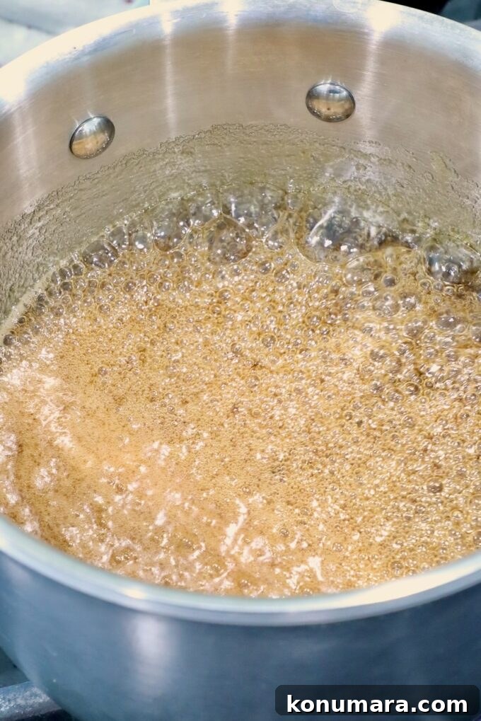 How to Smoke a Ham: Glaze, Time, and Temperature 8 Ham glaze bubbling in a silver pot, creating an amber, frothy liquid.