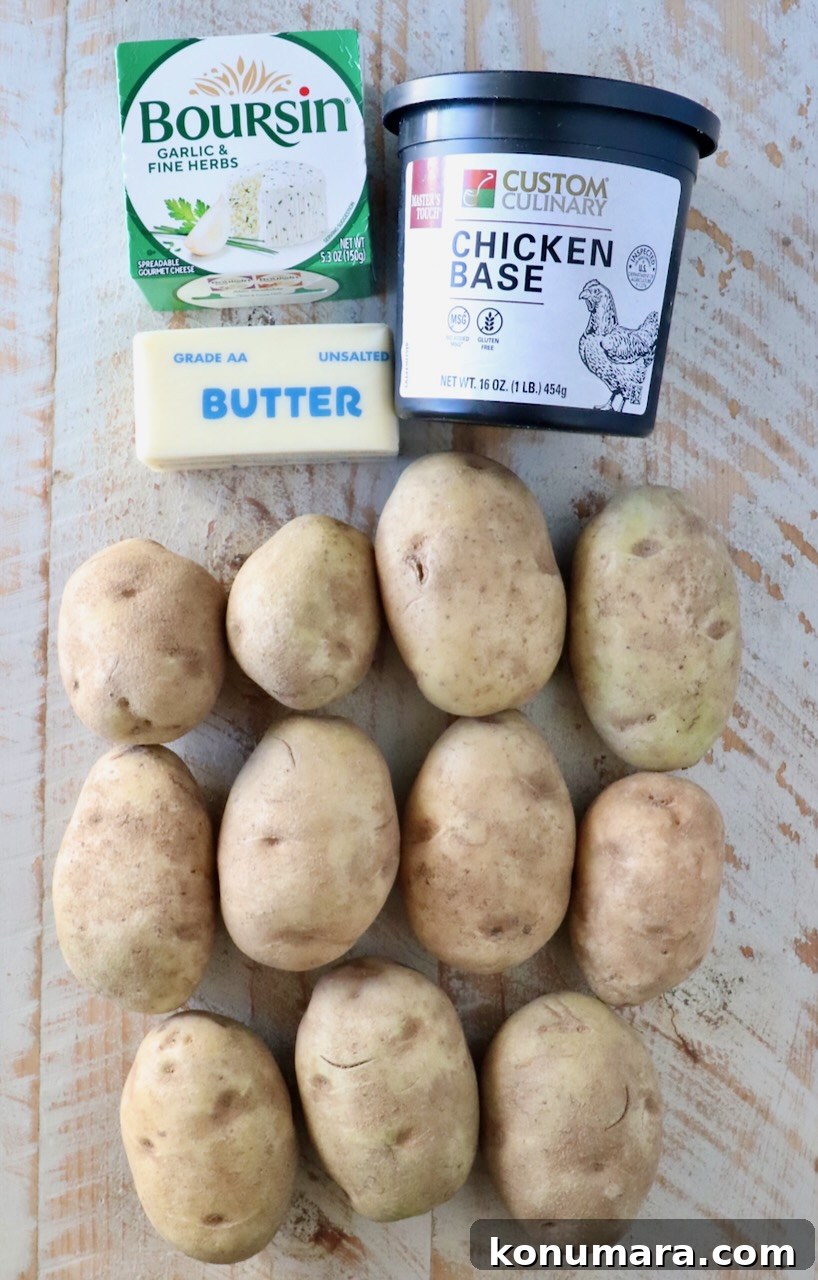Twelve potatoes arranged in three rows, accompanied by a box of Boursin cheese, a container of chicken base, and a stick of unsalted butter on a wooden surface.