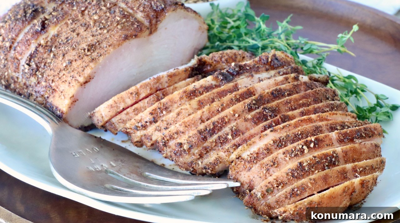 Sliced smoked turkey breast seasoned with spices on a white plate, garnished with fresh thyme. A silver carving fork rests beside it.