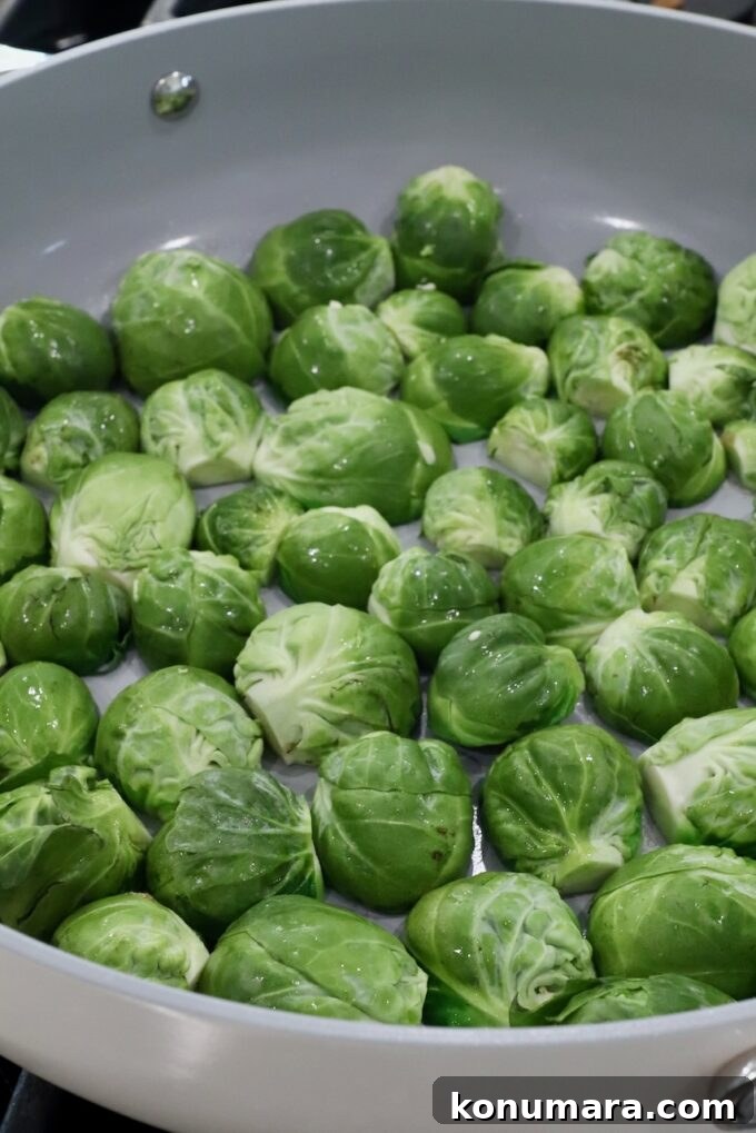 Fresh green Brussels sprouts evenly spread in a light-colored frying pan