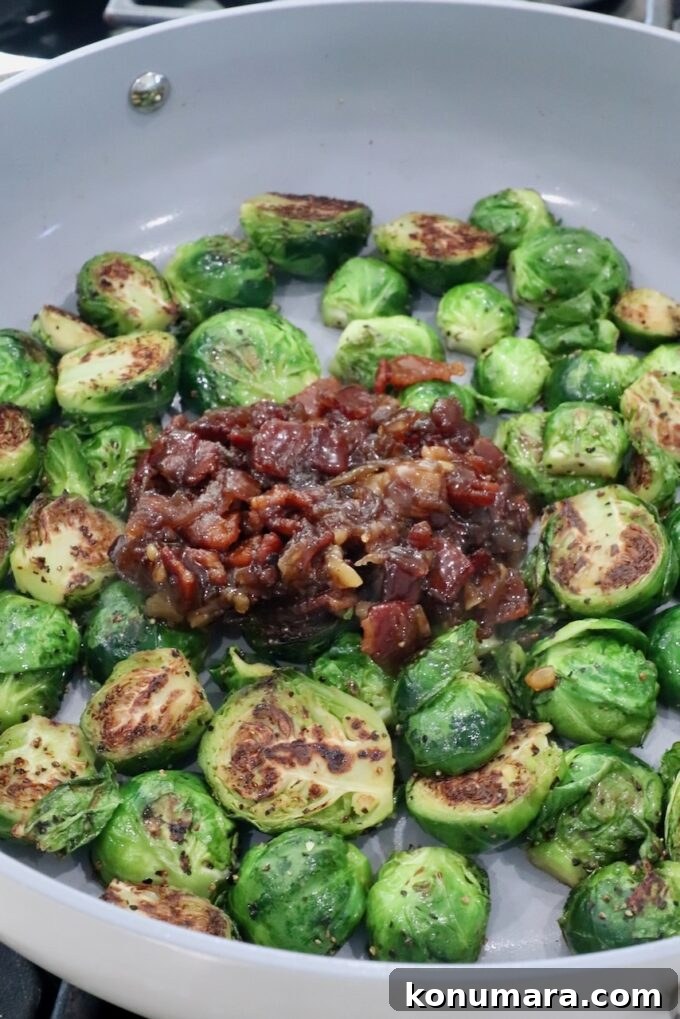 Pan-seared Brussels sprouts, halved and caramelized, surround a rich, savory bacon and onion jam in a gray skillet