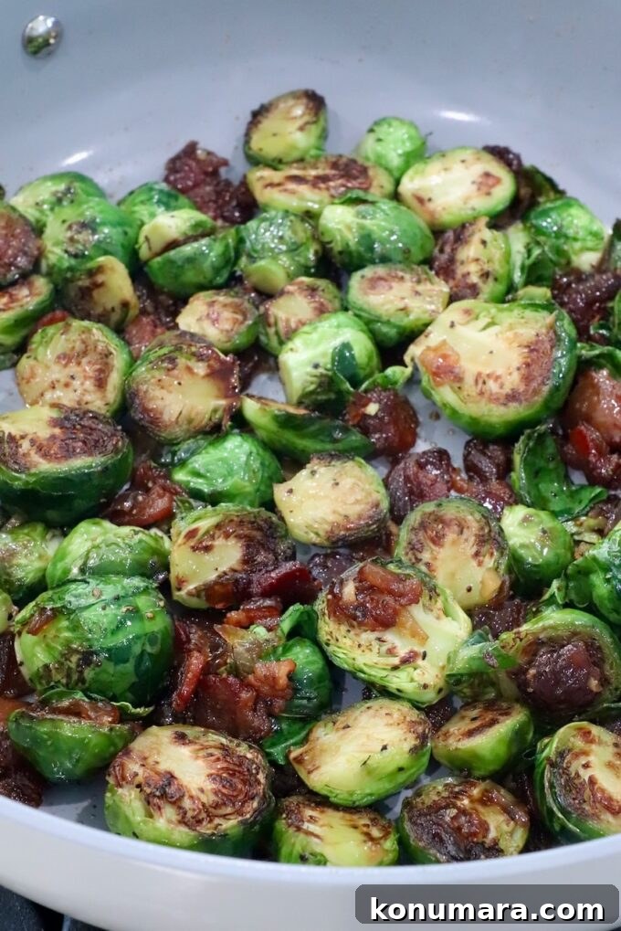 Caramelized Brussels sprouts with crispy, browned edges, mixed with bacon jam in a skillet