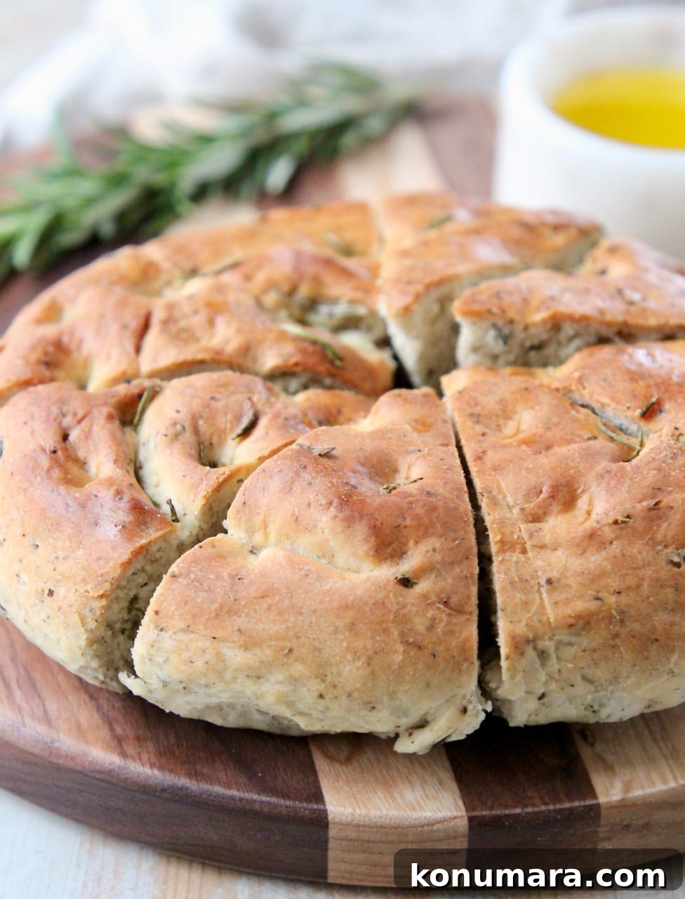 Round focaccia bread cut into diagonal slices on wood cutting board