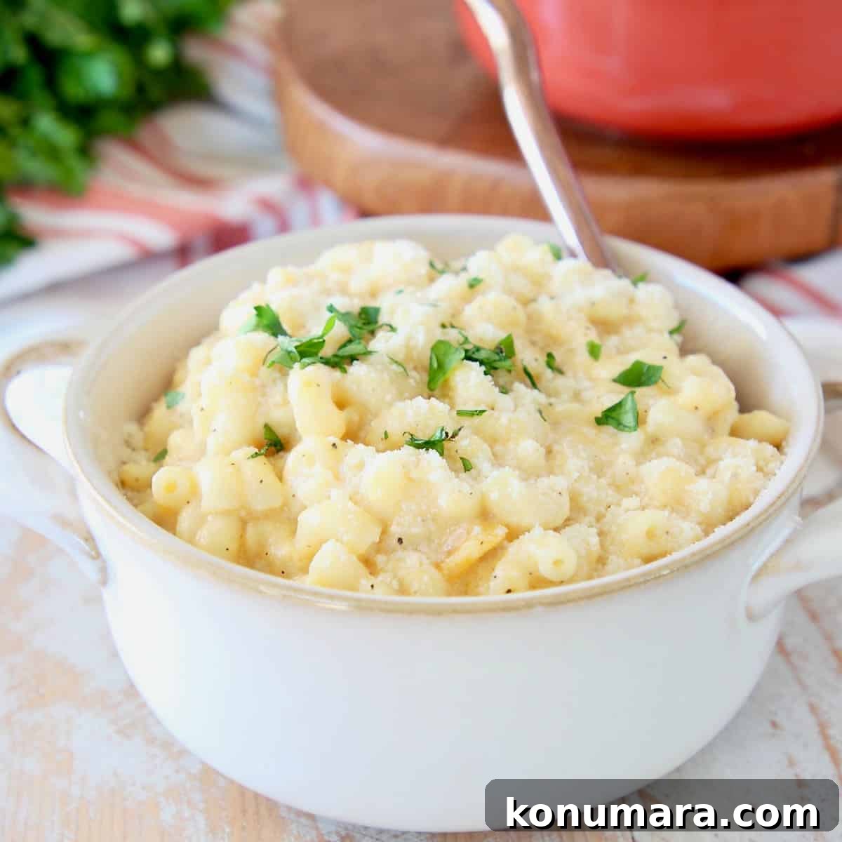 Butternut squash mac and cheese in white bowl with gold spoon