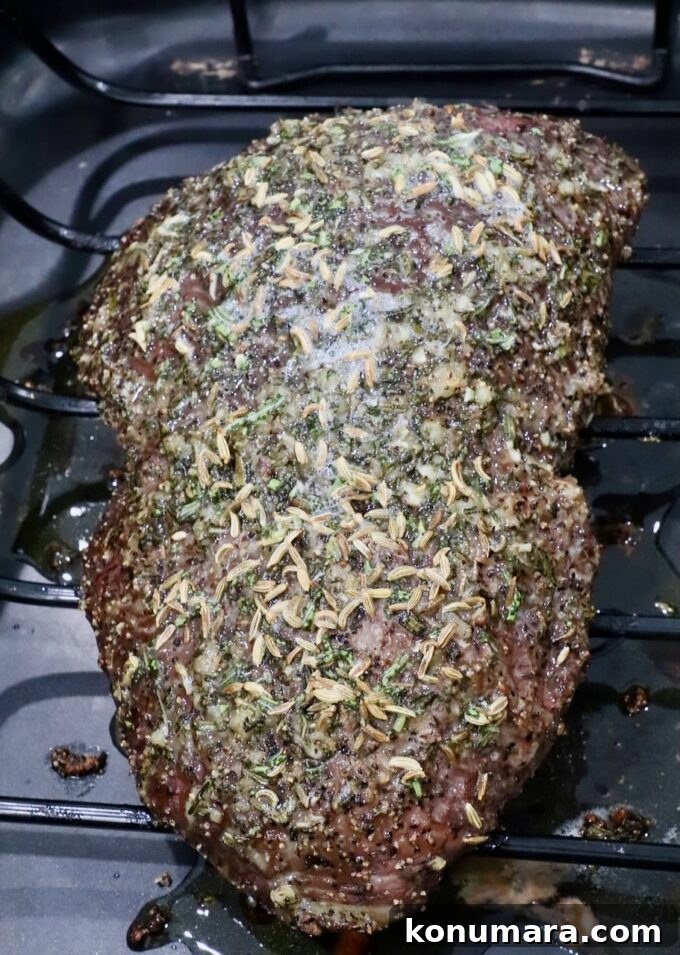 Sirloin Tip Roast Recipe for Tender, Juicy Results 6 A seasoned roast beef resting on a wire rack, topped with herbs and spices, in a dark roasting pan