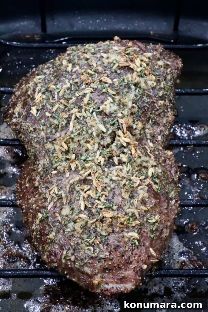 Sirloin Tip Roast Recipe for Tender, Juicy Results 7 A seasoned roast beef resting on a wire rack, topped with herbs and spices, in a dark roasting pan