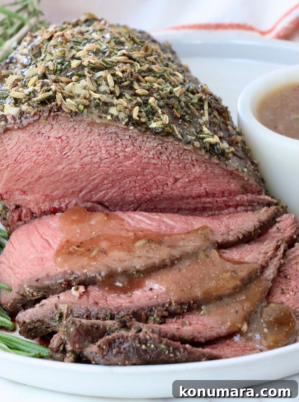 Sirloin Tip Roast Recipe for Tender, Juicy Results 8 Herb-crusted roast beef, thinly sliced and served on a white plate with brown gravy drizzled over the slices of beef.