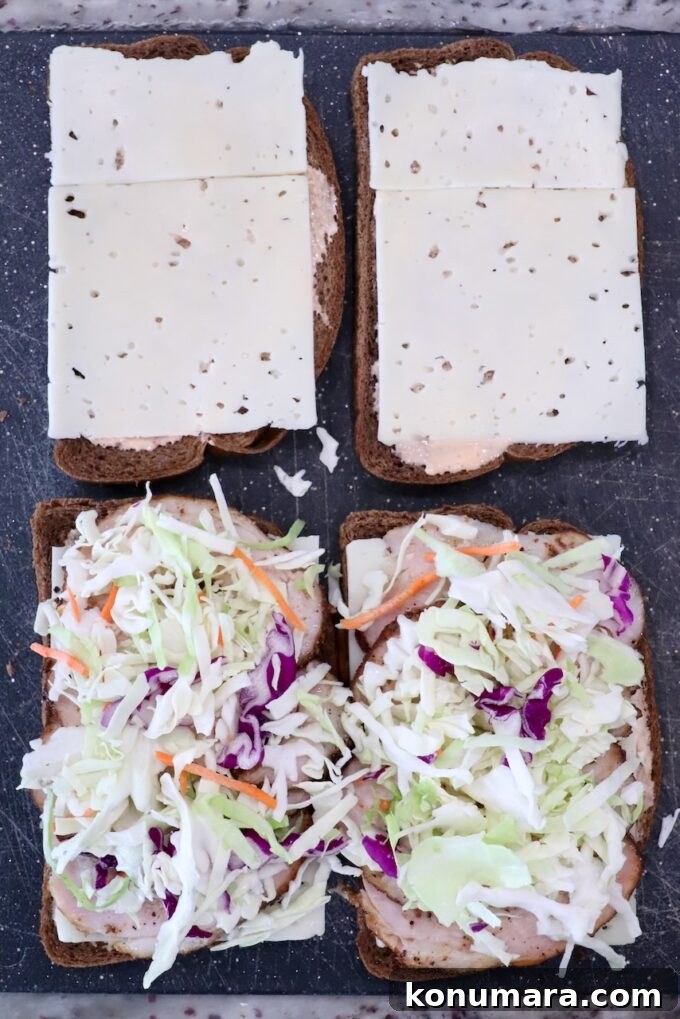 Open rye bread sandwiches: two with sliced cheese, two with coleslaw and meat, on a dark surface.