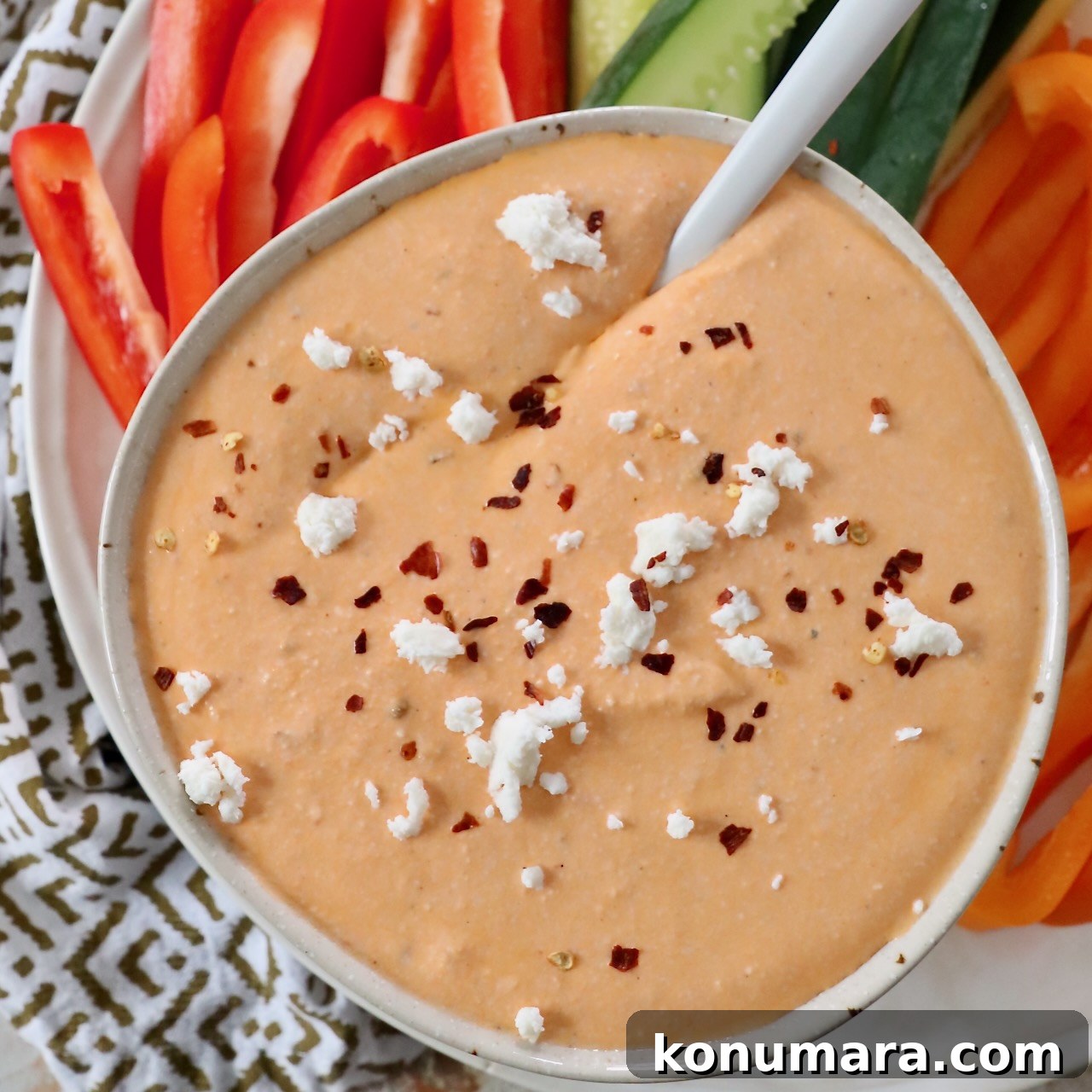 roasted red pepper feta dip in bowl topped with feta cheese crumbles and red pepper flakes