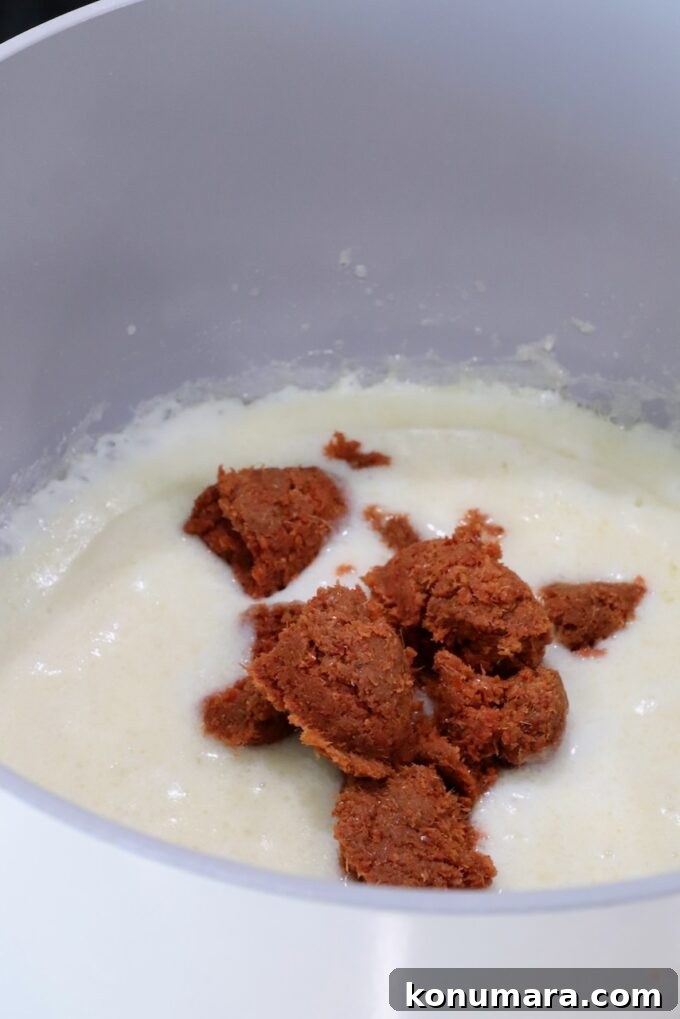 Curry Queso Dip Recipe 4 creamy roux sauce in a pot topped with spoonfuls of red curry paste