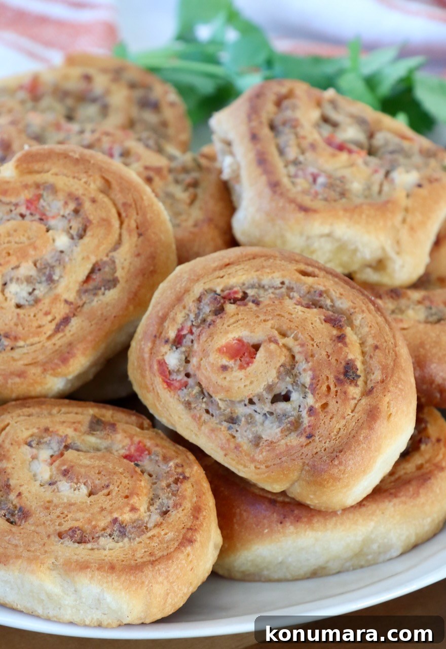 A plate of golden-brown sausage pinwheels with crispy edges and visible bits of sausage and tomato. Fresh parsley is in the background.