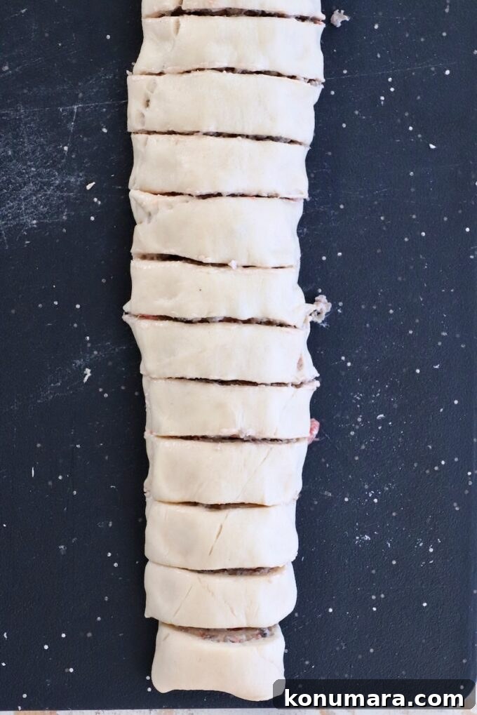 Dough rolled up with filling, sliced into even pieces, laid vertically on a black surface