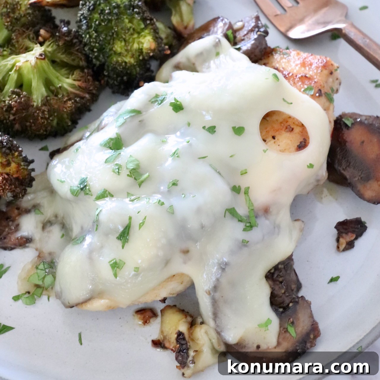 chicken covered in mushrooms and cheese on a plate with broccoli