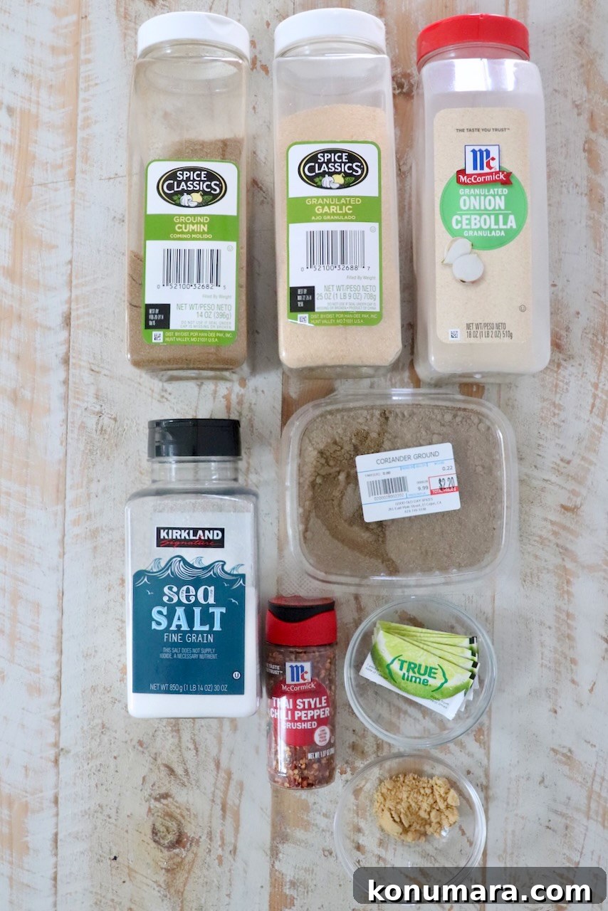 Homemade Thai Seasoning Blend: Authentic Recipe 3 Various spice containers arranged on a wooden surface: cumin, garlic, onion powder, sea salt, ground coriander, chili flakes, lime packets, ground ginger.