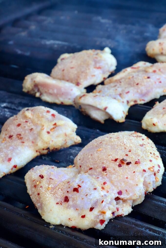 Authentic Thai Basil Chicken Stir-Fry (Pad Kra Pao) 6 Raw chicken thighs seasoned with spices, including red pepper flakes, placed on a grill.