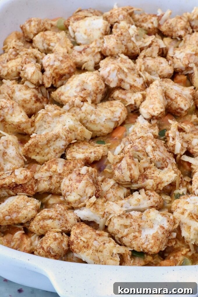 seasoned cubes of biscuit dough on top of pot pie filling in a baking dish