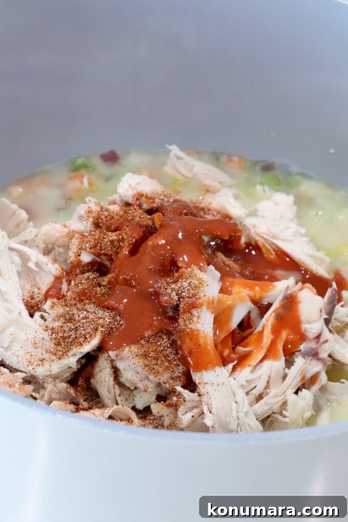 shredded chicken covered in seasonings and buffalo sauce in a pot with vegetables