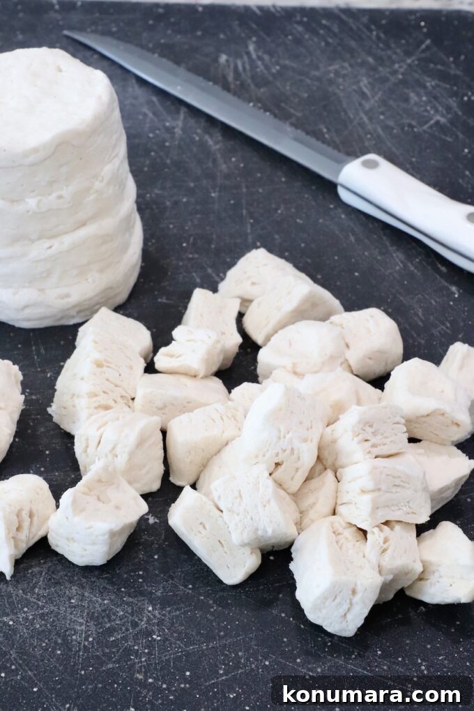 diced uncooked biscuits on a cutting board with a knife