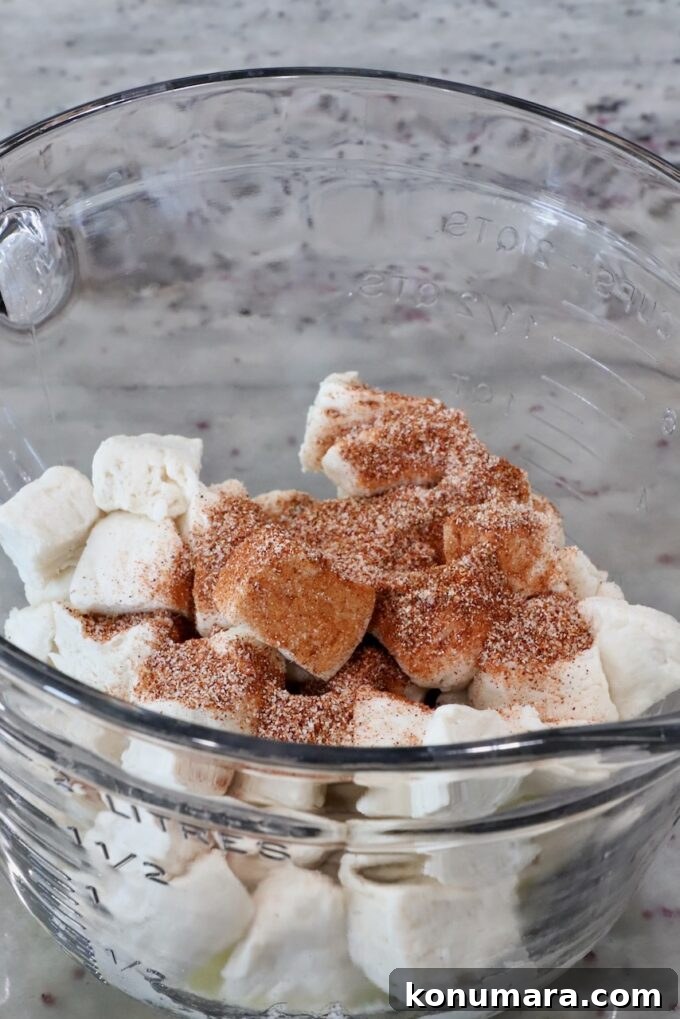 diced biscuits covered in seasoning in a glass bowl
