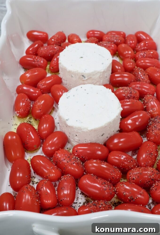 two rounds of Boursin cheese in a baking dish surrounded by cherry tomatoes