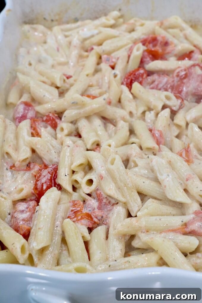 penne pasta in a creamy sauce with cherry tomatoes in a baking dish