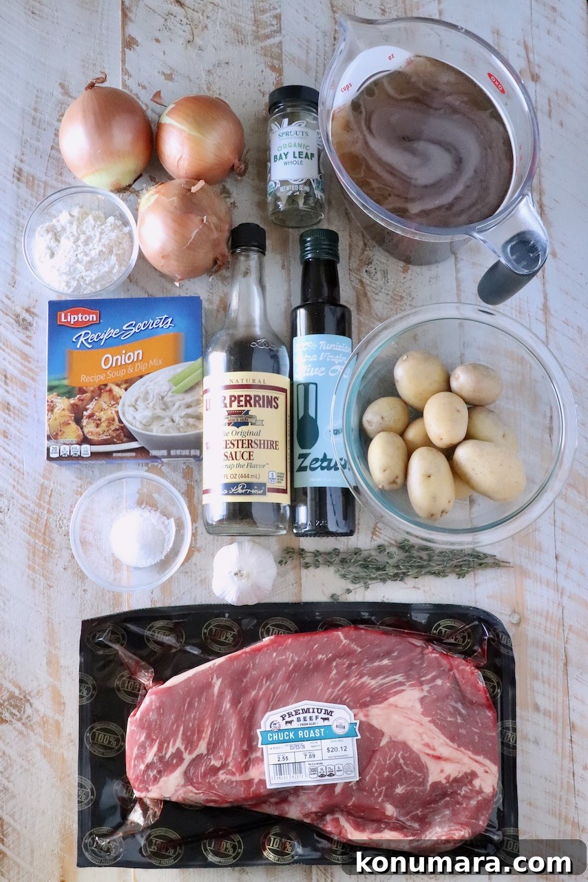 Overhead view of beef stew ingredients on a wooden surface: chuck roast, potatoes, onions, garlic, broth, Worcestershire sauce, olive oil, bay leaves, and seasonings.