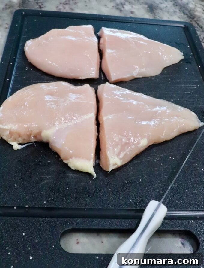 Crispy Air Fryer Chicken Sandwich Recipe 5 chicken breasts cut in half on a cutting board, sitting next to a knife