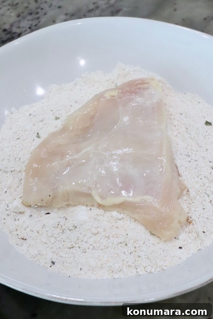 Crispy Air Fryer Chicken Sandwich Recipe 7 piece of chicken in a bowl of seasoned flour