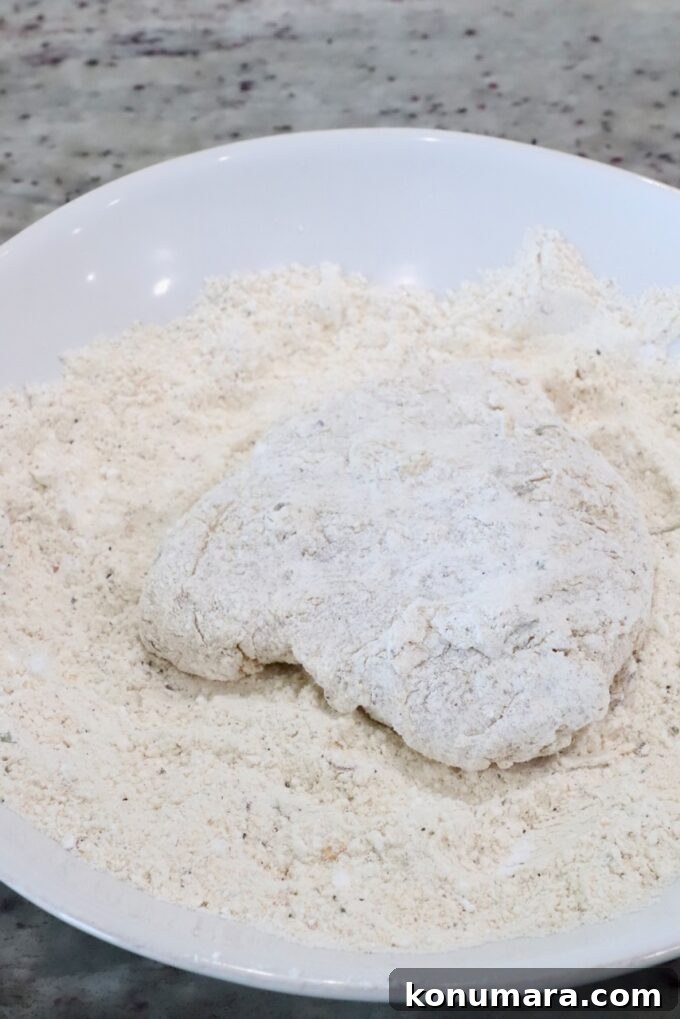 Crispy Air Fryer Chicken Sandwich Recipe 9 a piece of coated chicken in a bowl of flour