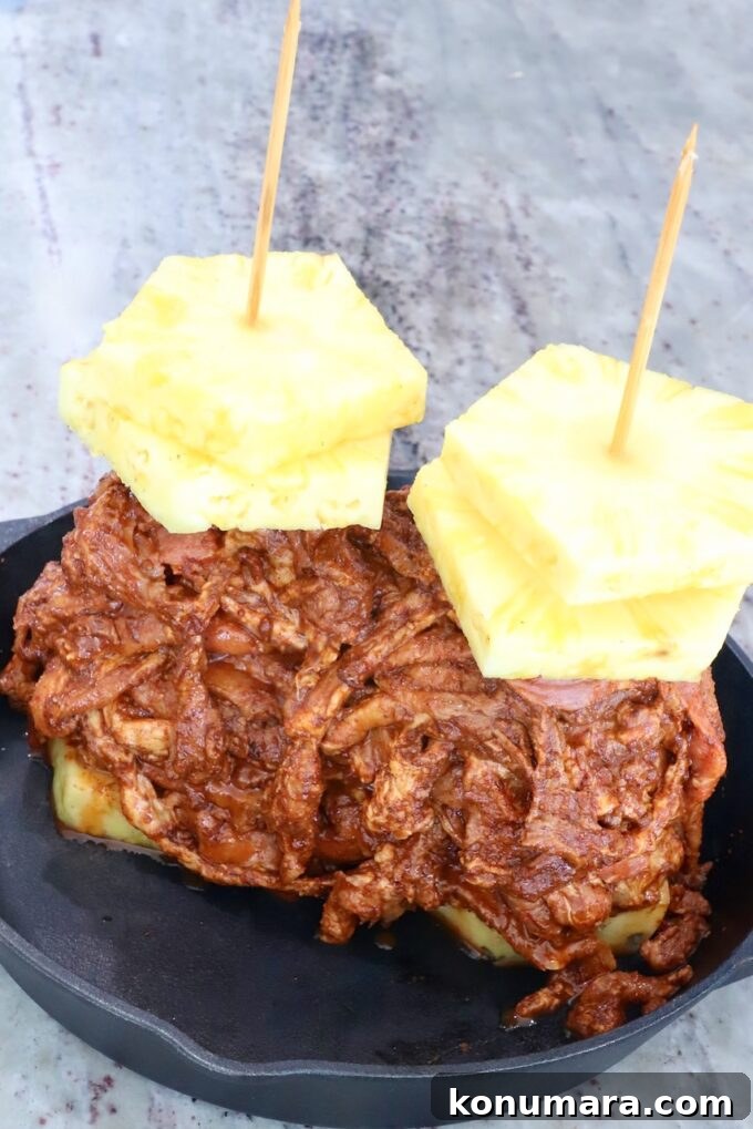 Slow-Roasted Al Pastor Pork Tacos 5 Thinly sliced marinated pork stacked up on skewers with pineapple slices in a cast iron skillet