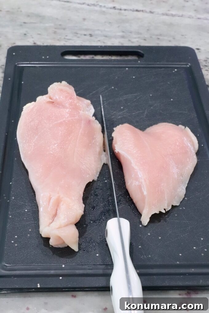 Chicken breast sliced in half on a cutting board