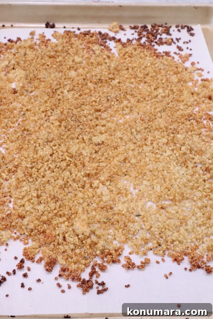 Cooked crispy quinoa spread out on a parchment-lined baking sheet