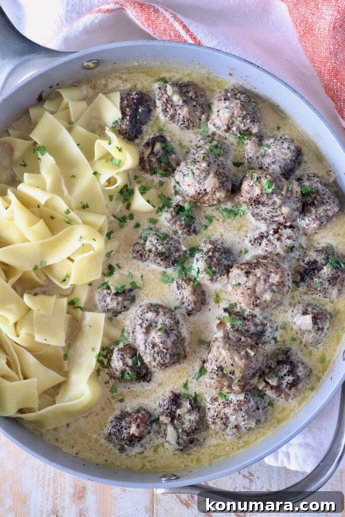 meatballs au poivre in a skillet with pappardelle pasta noodles