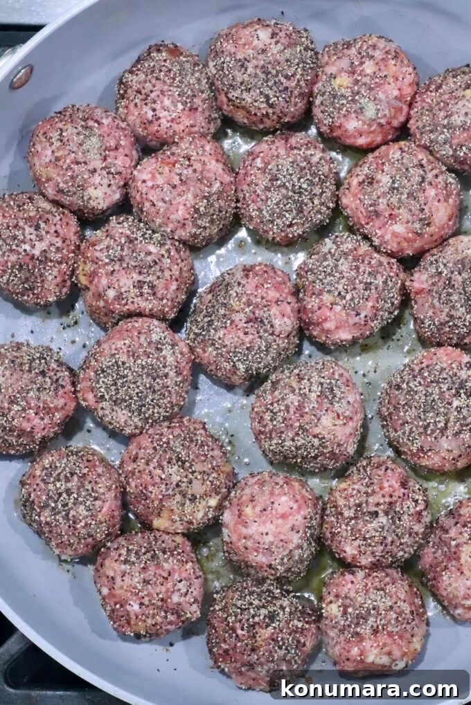 pepper coated raw meatballs in a skillet