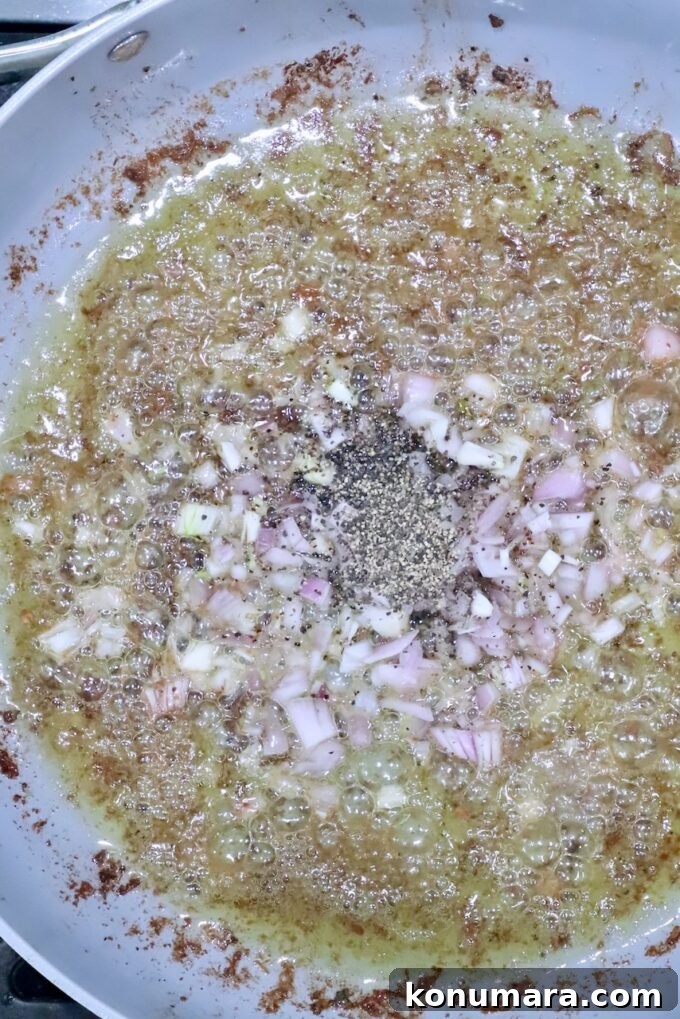 shallots and black pepper in liquid in a skillet