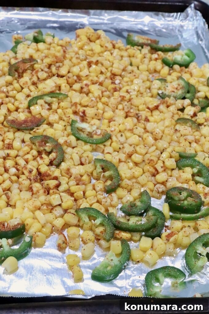 Mexican Street Corn Chicken Bowls Recipe with Cotija and Lime 5 Seasoned corn kernels and sliced jalapeños on a foil-lined baking sheet