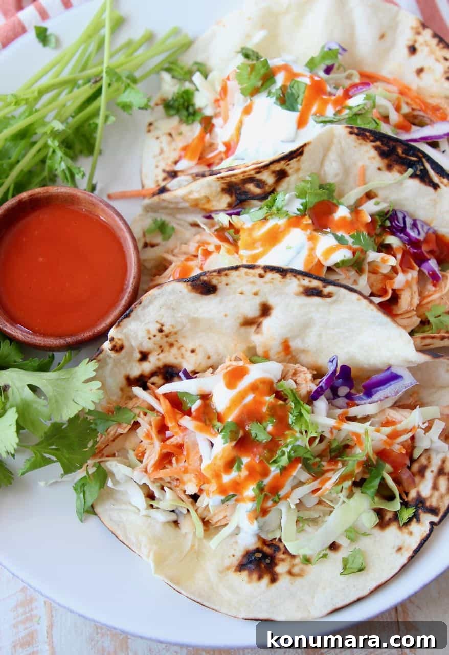 Buffalo chicken tacos on plate with side ramekin of buffalo sauce