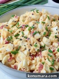 miso egg salad in a bowl topped with chopped chives and sesame seeds