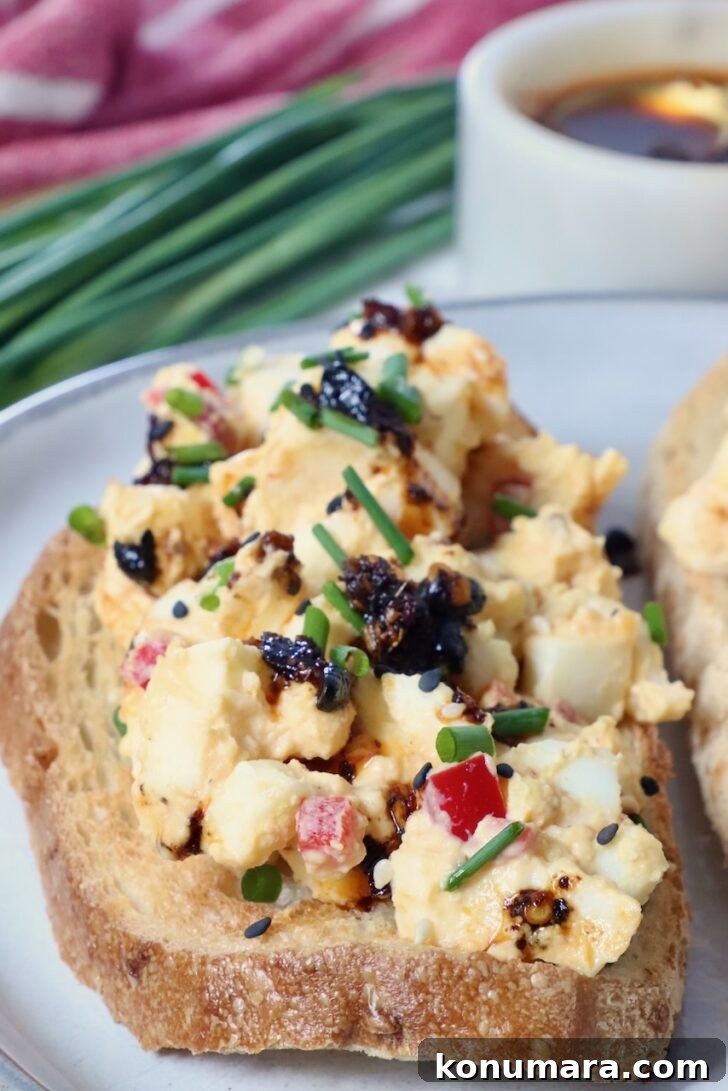 Spicy Miso Egg Salad with Chili Crisp Recipe 10 toast topped with miso egg salad on a plate, with fresh chives in the background