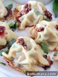 Thai Basil Chicken Dumplings Recipe with Chili Soy Dipping Sauce 13 Thai basil chicken dumplings on a plate topped with chili crisp and thai basil leaves