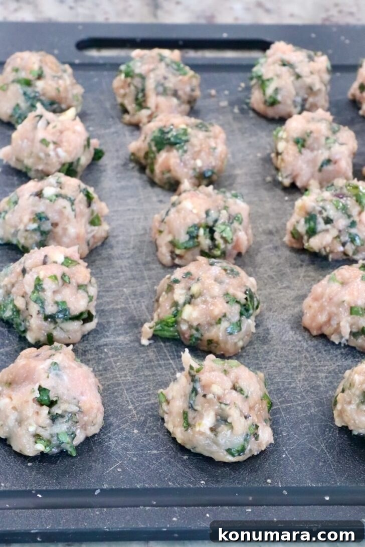 Thai Basil Chicken Dumplings Recipe with Chili Soy Dipping Sauce 8 raw Thai basil chicken meatballs on a black cutting board