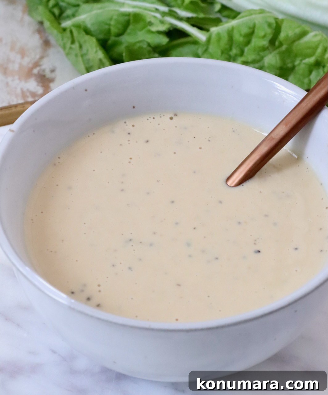 miso caesar dressing in a bowl with lettuce sitting behind the bowl