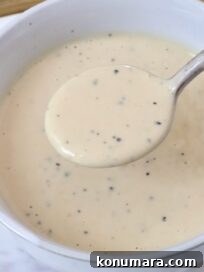 miso caesar dressing in a bowl with a spoon dipping the dressing out of the bowl