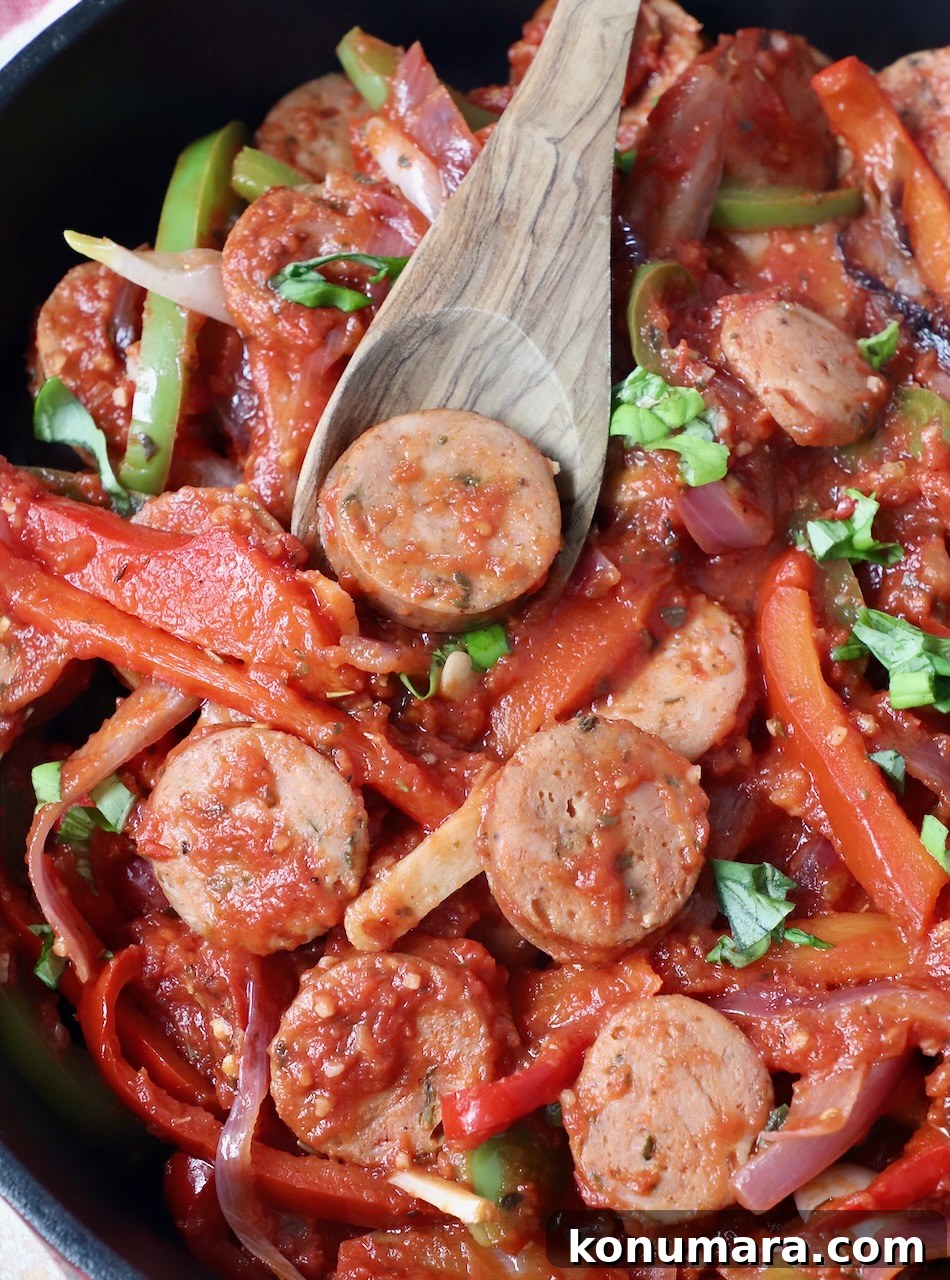 Classic Italian Sausage and Peppers Recipe 2 sliced sausage and peppers in skillet with wooden serving spoon