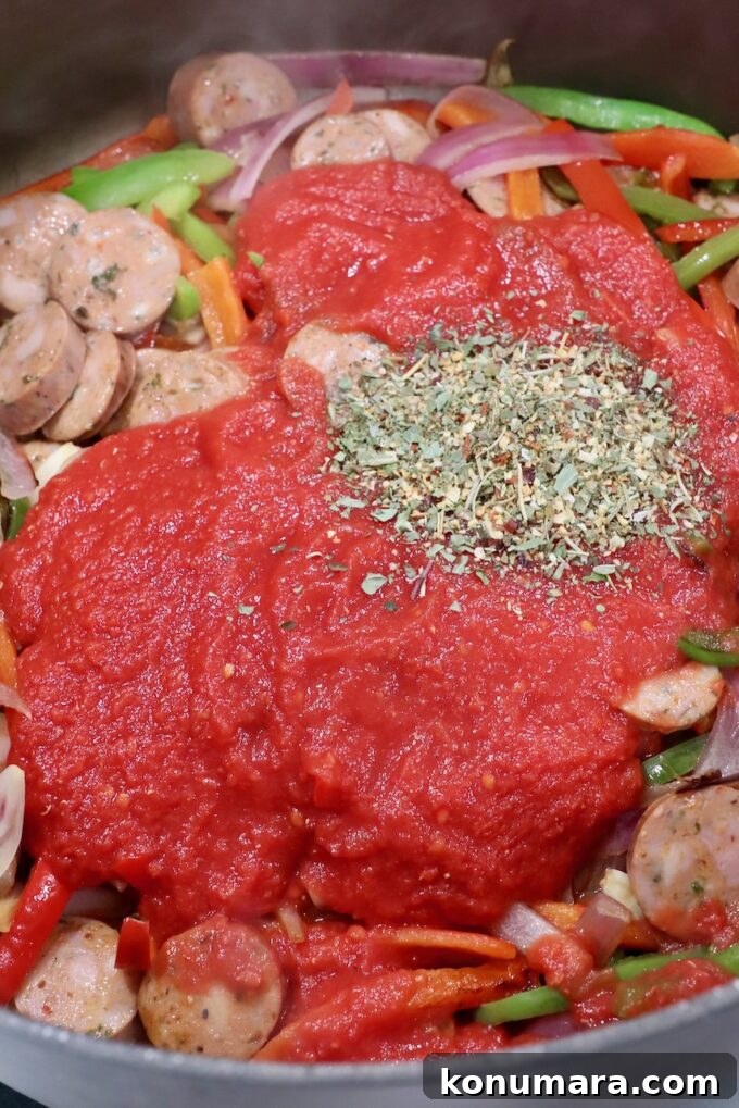 Classic Italian Sausage and Peppers Recipe 5 crushed tomatoes and Italian seasoning in pan with sausage and peppers