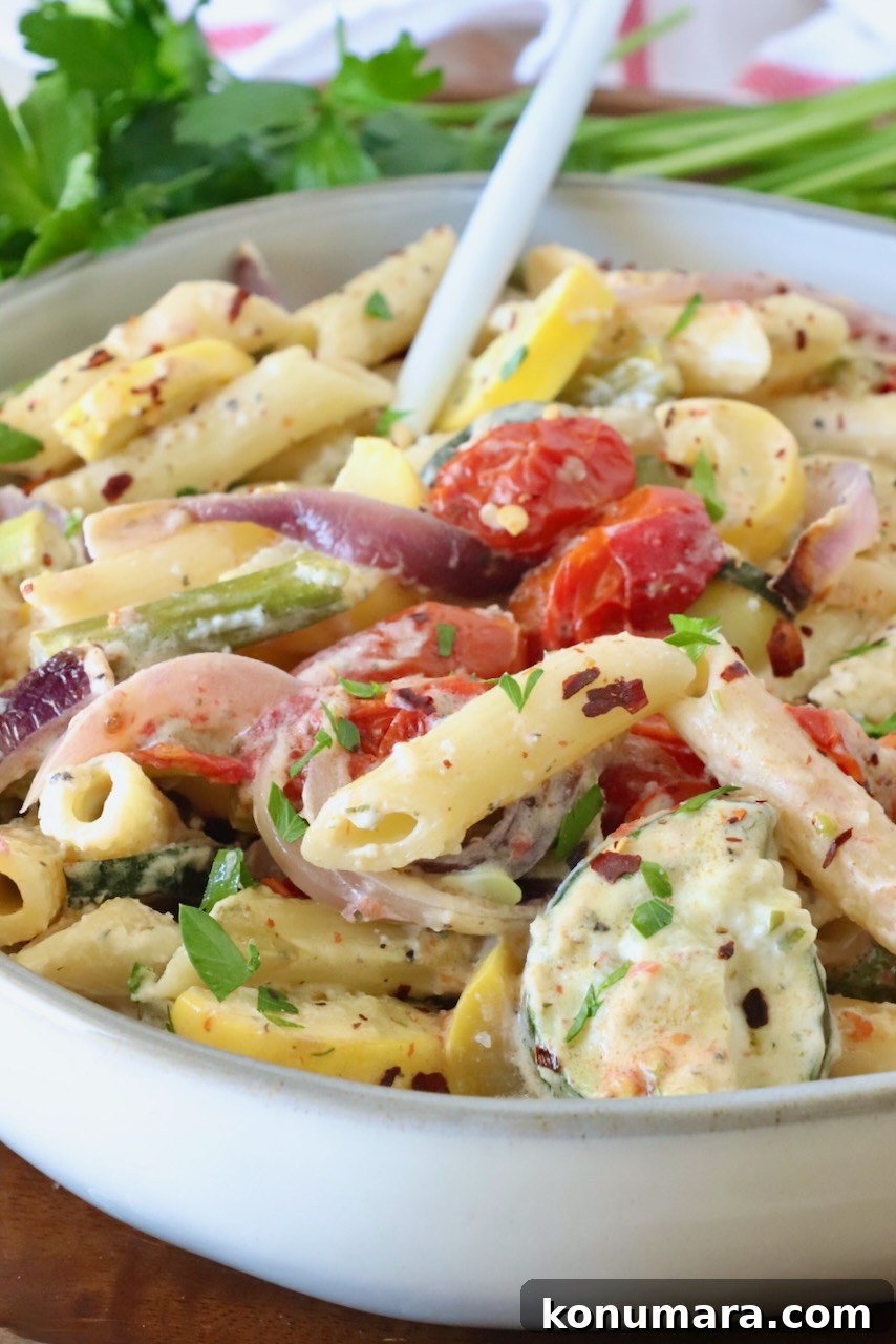 creamy pasta primavera in a bowl with a fork, with fresh parsley in the background